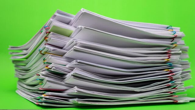 4K Stop motion of close-up stack overload document report paper with paperclip place decrease on green background, business and education concept footage paperless used. 