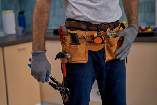Repair tools belt and wrench in hand of worker