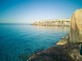 Cristal clear water and no people at the famous Cala Azzurra in Favignana, Italy. A perfect calm sunrise in this paradise island in the mediterranean sea