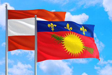 Guadeloupe and Austria national flag waving in the windy deep blue sky. Diplomacy and international relations concept.