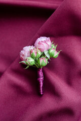 Groom's boutonniere made of peonies on a purple fabric background. wedding details and accessories