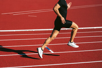 Obraz premium Fitness man running on the red running track. Copy space. Close Up. Lifestyle and sports