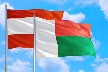 Madagascar and Austria national flag waving in the windy deep blue sky. Diplomacy and international relations concept.