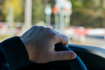 A man's hand holds the steering wheel of a modern car