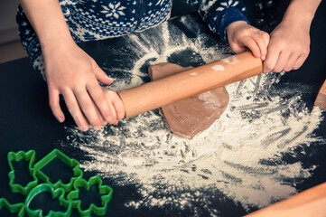 Close up of child hands making Christmas cookies and rolling ginger dough. Christmas and New Year holidays