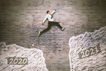 Asian businessman jumping gap on the bricks wall