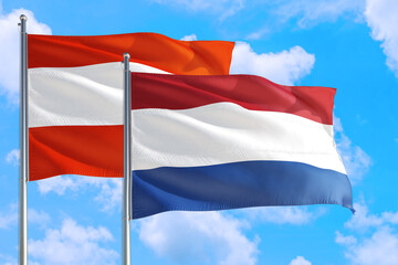 Fototapeta na wymiar Netherlands and Austria national flag waving in the windy deep blue sky. Diplomacy and international relations concept.