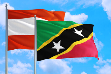 Saint Kitts And Nevis and Austria national flag waving in the windy deep blue sky. Diplomacy and international relations concept.