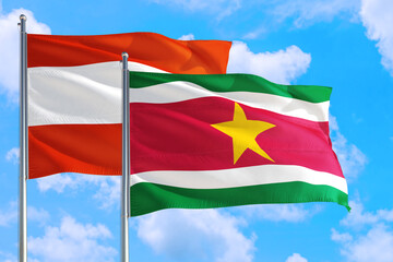 Suriname and Austria national flag waving in the windy deep blue sky. Diplomacy and international relations concept.