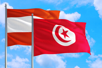 Tunisia and Austria national flag waving in the windy deep blue sky. Diplomacy and international relations concept.