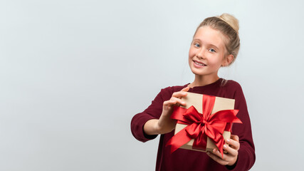 Portrait of happy blonde girl holding gift decorated with ribbon. Studio shot white background. Copy space for your text