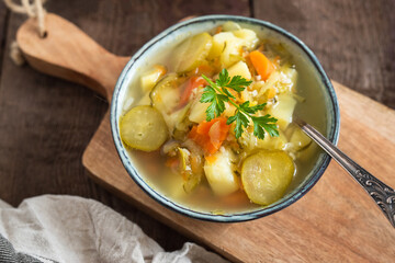 Pickled cucumber soup with vegetables on a wooden background