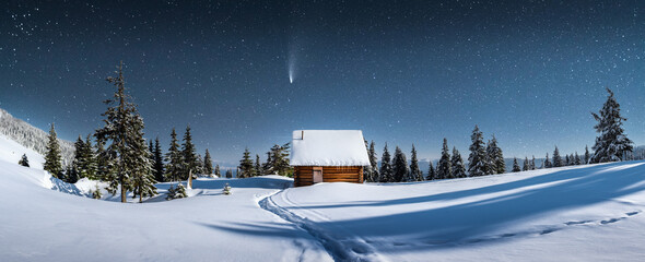 Fantastic winter landscape panorama with wooden house in snowy mountains. Starry sky with Milky Way and snow covered hut. Christmas holiday and winter vacations concept