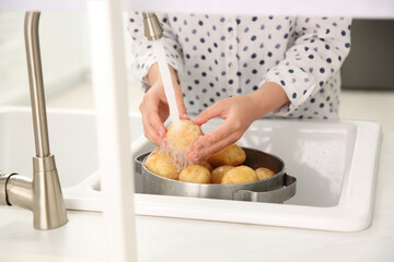 Obraz na płótnie Canvas Woman washing fresh potatoes in kitchen sink, closeup