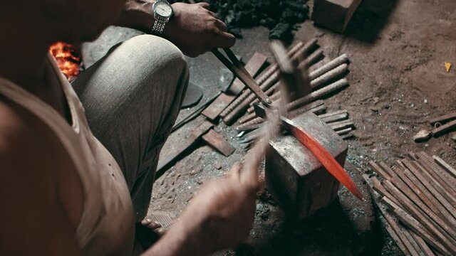 Man hammering a hot metal knife piece on anvil