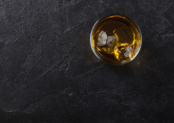 Glass with ice cubes of scotch whiskey on black background.