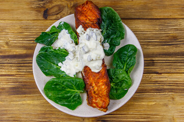 Grilled salmon fillet with spinach and tartare sauce on wooden table. Top view