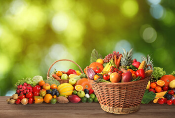 Wicker baskets with different fresh organic vegetables and fruits on wooden table against blurred green background