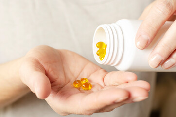 Caucasian female hands with yellow pills and medicine bottle closeup