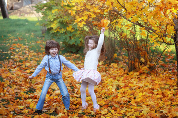 Fototapeta premium Young family on a walk in the autumn park on a sunny day. Happiness to be together.