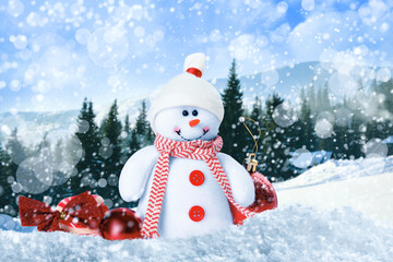 Cute toy snowman with Christmas balls in winter forest
