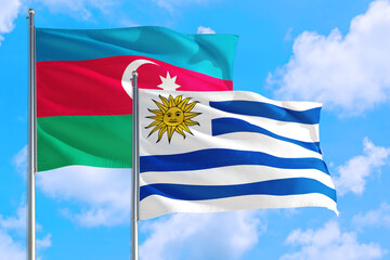 Uruguay and Azerbaijan national flag waving in the windy deep blue sky. Diplomacy and international relations concept.