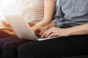 Naklejka premium Group of casual dressed business people working at meeting or conference in sunny office, close-up of hands. Businessman using laptop computer