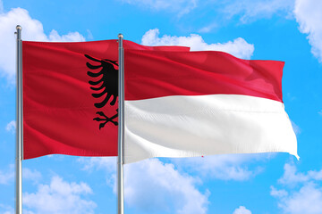Fototapeta na wymiar Indonesia and Albania national flag waving in the windy deep blue sky. Diplomacy and international relations concept.