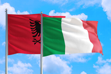 Italy and Albania national flag waving in the windy deep blue sky. Diplomacy and international relations concept.