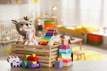 Set of different cute toys on wooden table in children's room - obrazy, fototapety, plakaty
