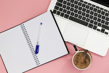 spiral notebook with laptop and white coffee on pink background