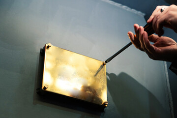 Installation of a gold colored metal plate. The process of screwing the screws into the memorial...