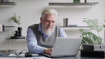 Happy an elderly man with a gray beard completed task and triumphing with raised hands