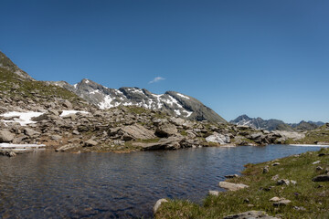 Obraz premium Wild lake Southtirol Italia Val pusteria Alpine pastures with a deep blue lake, green meadows and a blue sky with fleecy clouds, in summer