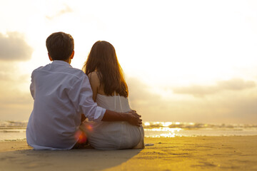 Couple in love watching sunset together on the beach travel summer holidays. People romance concept.