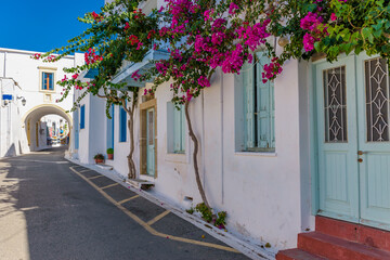 Fototapeta na wymiar Traditional alley with narrow street, whitewashed houses and a blooming bougainvillea in chora Kythira island, Greece.