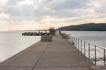 Long concrete pier with wooden benches..