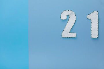 Handmade white numbers 21 are on a blue background. The concept of a creative Christmas and new year 2021, blank for advent calendar. Copy space.