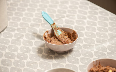 A bowl of mixed butter, cinnamon and shuger with a blue plastic knife..