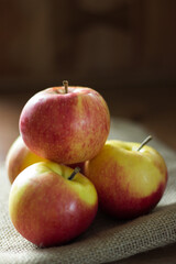 Stack of four red organic apples on brown background