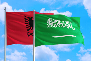 Saudi Arabia and Albania national flag waving in the windy deep blue sky. Diplomacy and international relations concept.