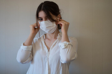A young woman in a mask with earphones, a young woman holding earphones in a face mask, a person with headphones, listening to the music with a face mask