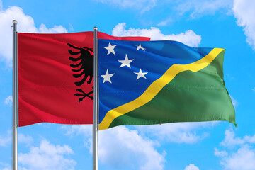 Solomon Islands and Albania national flag waving in the windy deep blue sky. Diplomacy and...