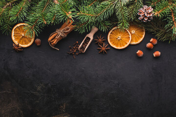 Fototapeta na wymiar Christmas black background with fir branches, spices,oranges. View from above with copy space