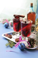 
Traditional Christmas drink, cups with mulled wine, spices, fir branches and illumination on a bright blue background, the concept of celebration, home comfort, winter