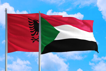 Sudan and Albania national flag waving in the windy deep blue sky. Diplomacy and international relations concept.