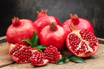 Several ripe pomegranate fruits and an open pomegranate with pomegranate leaves on a wooden old...