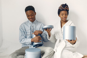 Couple with presents. Girl in a white bahrobe. Black people in a studio.