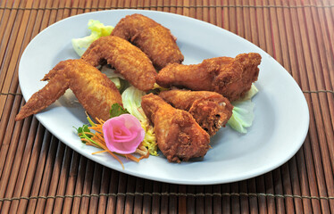 Deep Fried Chicken Wings on white plate, on the bamboo mat background.