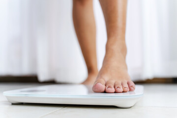 Close up woman bare feet standing on digital electronic scales at home, loss weight concept.